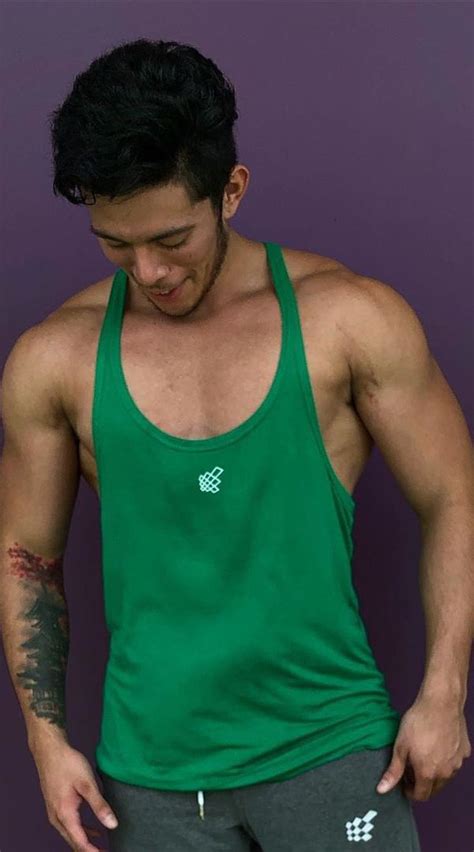 A Man In Green Tank Top Standing Next To Purple Wall With His Hands On