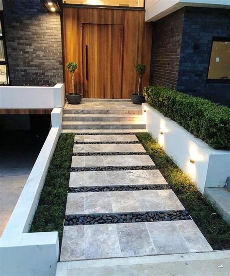 A Modern House With Stone Steps Leading Up To The Front Door And Side