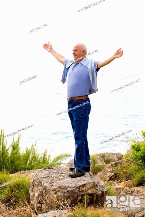 Man Standing On Cliff Looking Out At Ocean Stock Photo Picture And