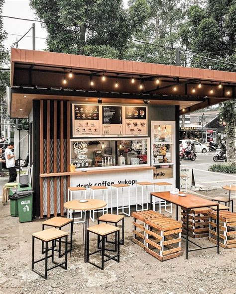 An Outdoor Coffee Shop With Wooden Tables And Stools On The Ground