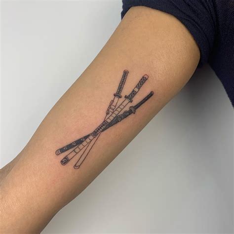 A Tattoo On The Arm Of A Woman With Three Crossed Knives