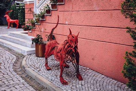 A red dog statue on a sidewalk next to a building · Free Stock Photo