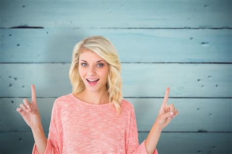 Premium Photo Pretty Blonde Smiling And Pointing Up Against Painted