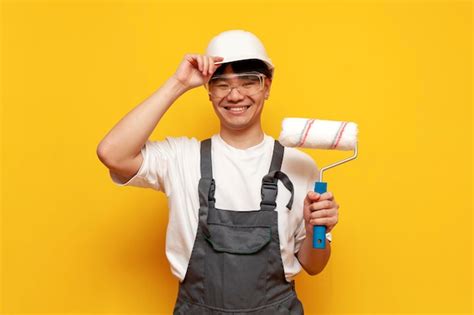 Premium Photo Asian Male Painter In Helmet And Overalls Holds Roller