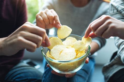 Friends Sharing And Eating Potato Chips At Home Party Together Stock