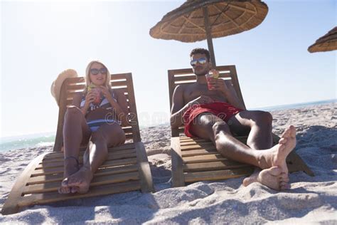 Caucasian Couple Sitting On Deck Chairs At The Beach Stock Image