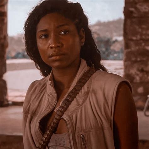 A Woman Standing In Front Of A Stone Wall With Her Hand On Her Hip And