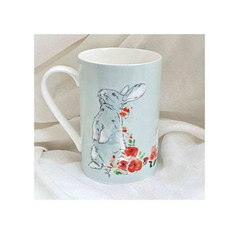 A Coffee Mug With An Image Of A Rabbit And Flowers Painted On The