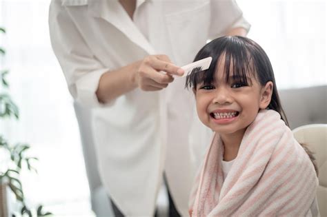 Premium Photo Asian Mother Cutting Hair To Her Daughter In Living