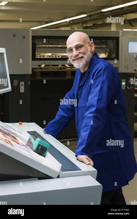 Portrait Of Smiling Mature Worker Standing By Equipment At Printing
