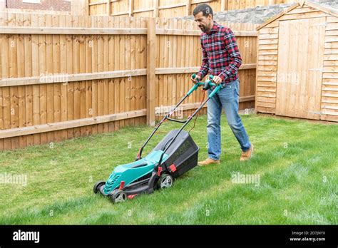 Mid Adult Man Cutting Grass With Lawn Mower At Backyard Stock Photo Alamy