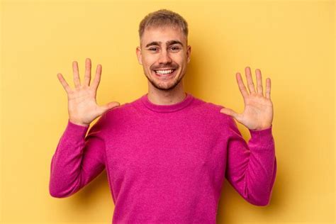 Jovem homem caucasiano isolado no fundo amarelo mostrando o número dez