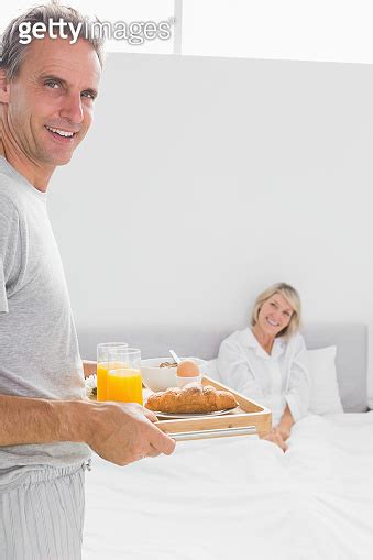 Happy man bringing breakfast in bed to his partner 이미지 494257763 게티