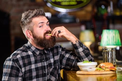 Homem barba bebe cerveja come menu de hambúrguer desfrute de