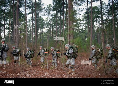 Soldiers march in a column formation with their rucks and weapons ...