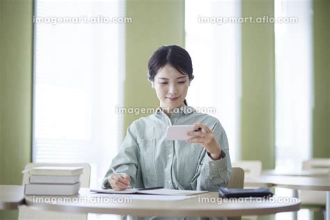 図書館にてスマートフォンを使用して勉強をする日本人の女性 （人物）の写真素材 225856941 イメージマート