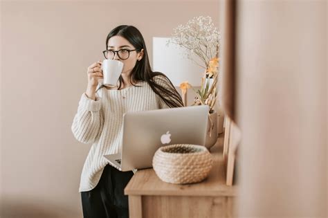 Woman Drinking Coffee Whilebstanding Near A Laptop · Free Stock Photo