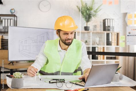 Foto De Competent Architect Male Sitting On Desk Indoors With Digital