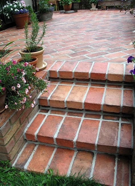 A Brick Patio With Flowers And Potted Plants On The Steps Leading Up To It