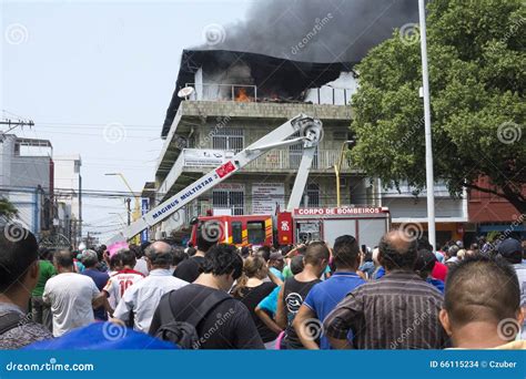 Two Firefighters Watch A Third Fireman Spraying Water On A Store In A