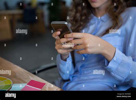 Mid Section Of Female Graphic Designer Using Mobile Phone In Office