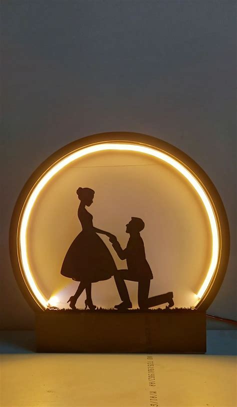 A Silhouette Of Two People Holding Hands In Front Of A Circular Light