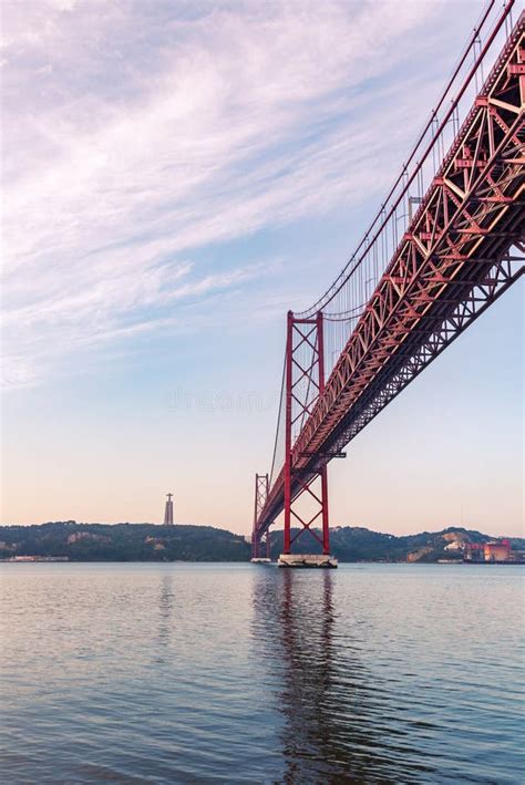 25 De Abril Bridge At Sunrise With The Cristo Rey De Almada Monument In