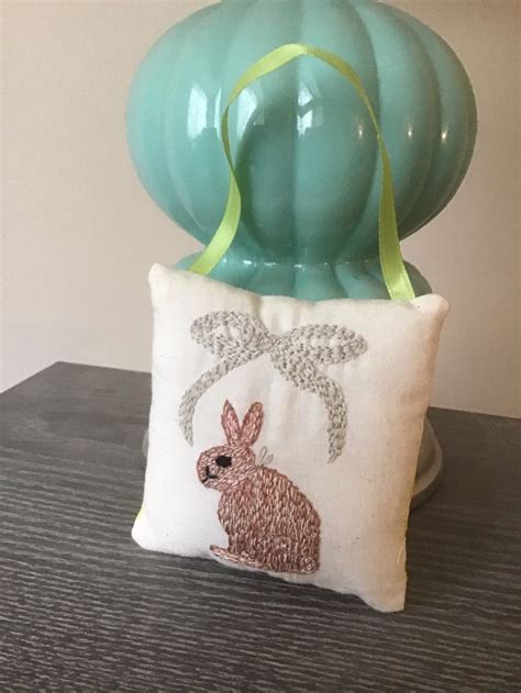 A Pillow With A Bunny On It Sitting Next To A Vase