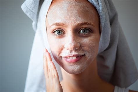 Premium Photo Portrait Of Smiling Young Woman Applying Cream On Face