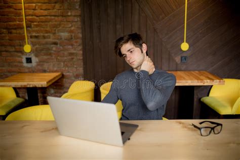 Handsome Man Suffering From Neck Pain In Office At Laptop Stock Photo