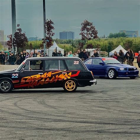 Two Cars With Flames Painted On Them In A Parking Lot Next To Other