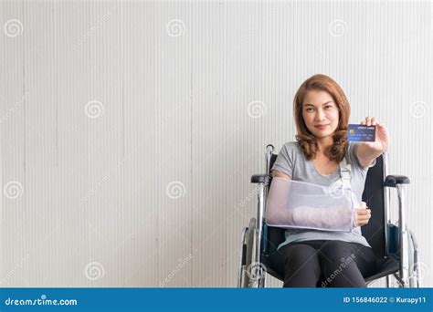 Female Patients With Broken Arms Wheelchair Holding Credit Cards Stock