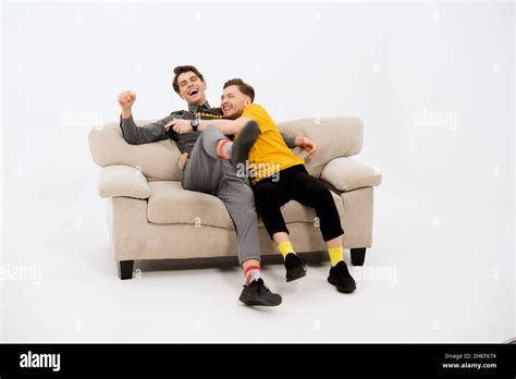Amis amusants sur le canapé blanc Deux gars sur le canapé rient Couple gay amoureux Deux jeunes