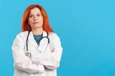 Premium Photo Serious Mature Redheaded Female Doctor Standing With Arms Crossed