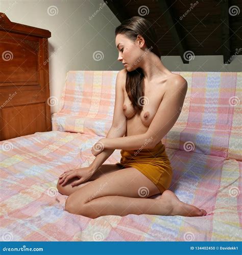Modelo Novo Bonito Que Levanta O Assento Nude Na Cama Foto De Stock