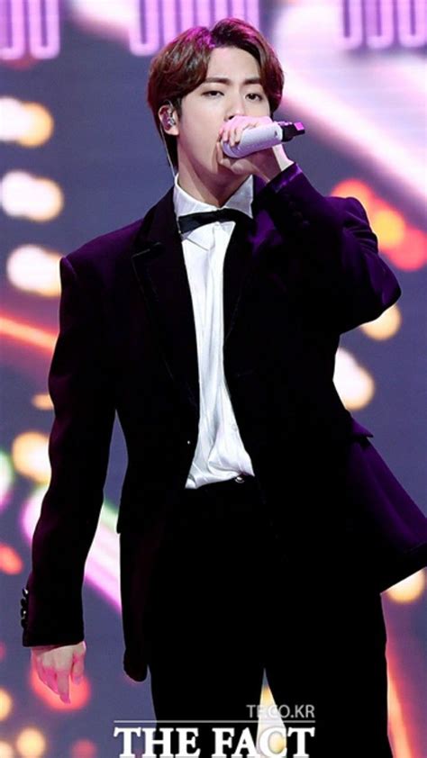 A Man In A Tuxedo Singing Into A Microphone