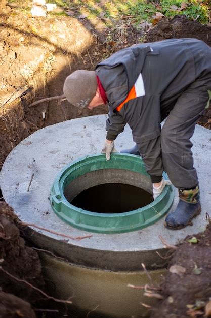 Premium Photo A Worker Installs A Sewer Manhole On A Septic Tank Made