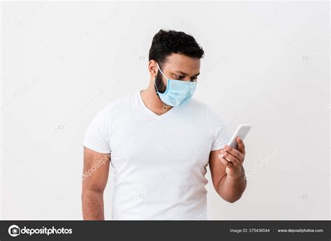 African American Man Medical Mask Using Smartphone White Wall Stock