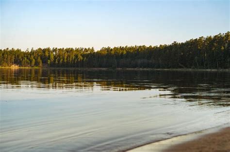 Belo pôr do sol no lago ladoga praia de areia e céu azul floresta de