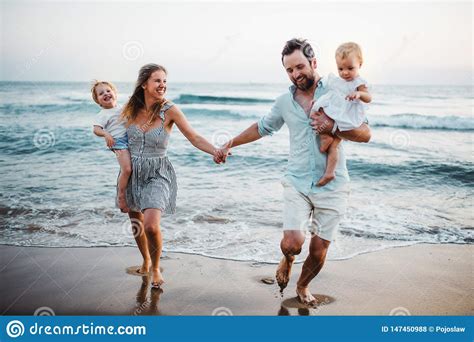 Familia Joven Con Dos Ni Os Del Ni O Que Caminan En La Playa El