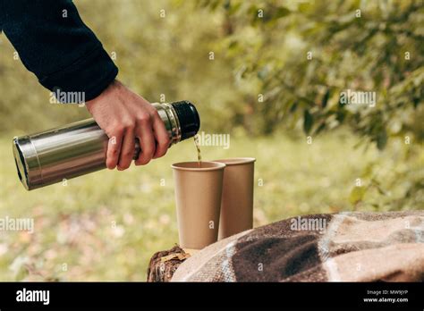 Cropped Shot Of Man Pouring Hot Tea From Thermos In Paper Cups Stock