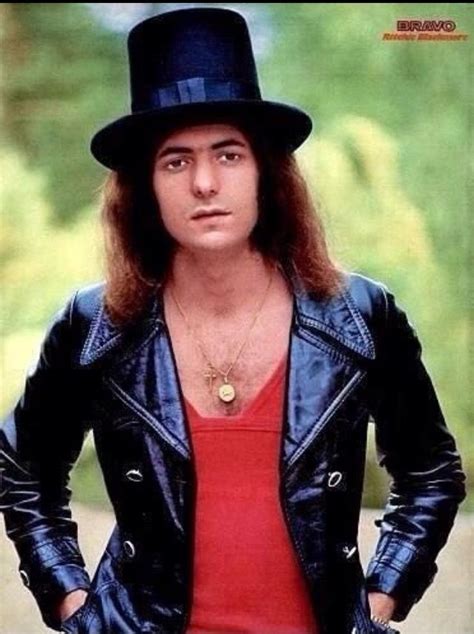 A Man With Long Hair Wearing A Black Hat And Leather Jacket Is Posing For The Camera