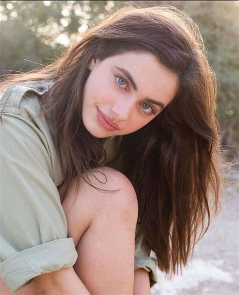 A Beautiful Young Woman Sitting On The Ground Posing For A Photo In