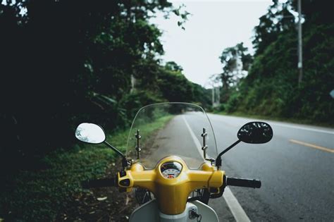 Premium Photo Motor Scooter Parked On Roadside Against Trees