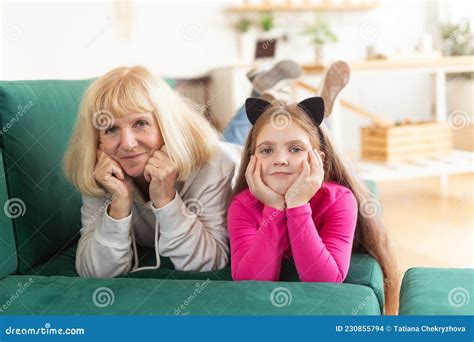 Happy Granddaughter And Grandmother Lying On Sofa In Funny Pose