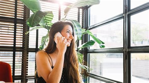 Uma mulher jovem e atraente falando no telefone inteligente Foto Grátis