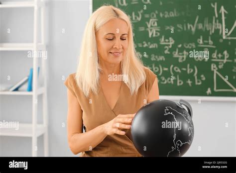 Mature Geography Teacher With Globe In Classroom Stock Photo Alamy