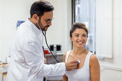 Young Doctor Listen To Female Patient Heart Chest With Stethoscope At