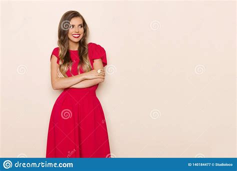 Happy Eautiful Young Woman In Red Dress Is Standing With Arms Crossed