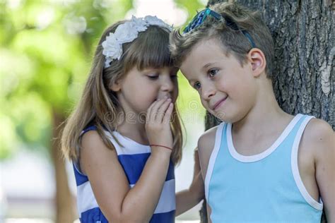 O Menino E A Menina Bonitos Pequenos Sentam Se Na Grama E No Jogo Foto